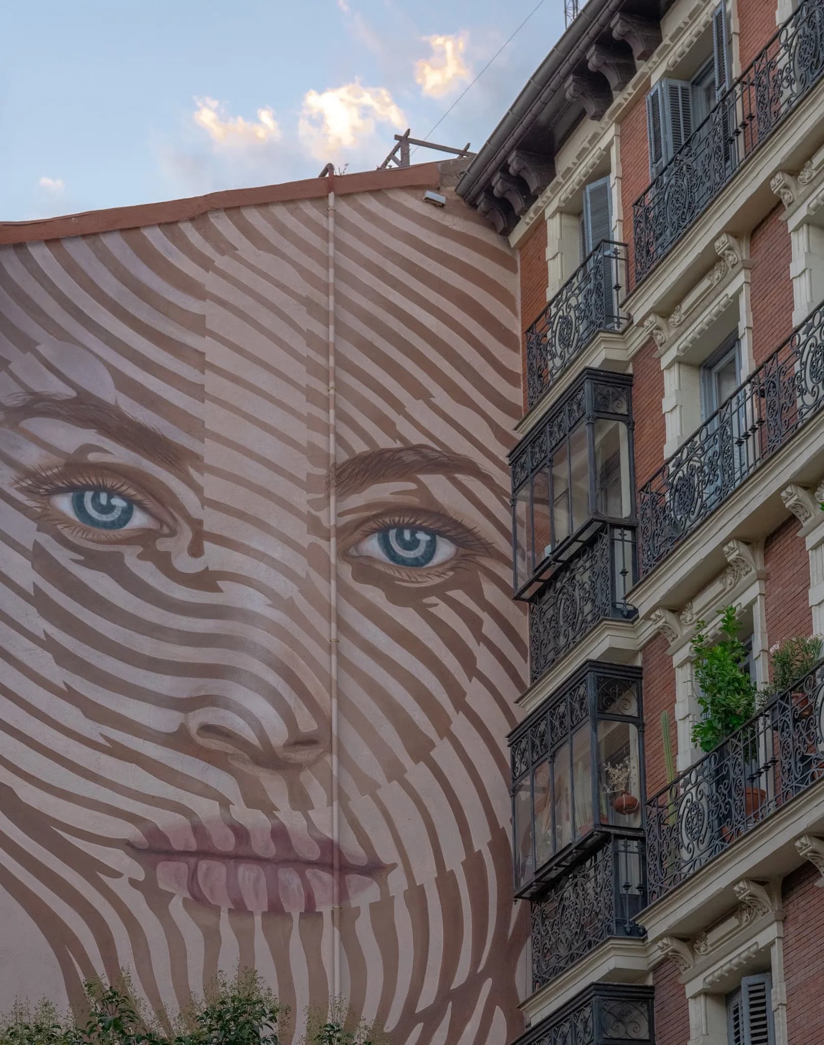A large painted face beside ornate Madrid balconies